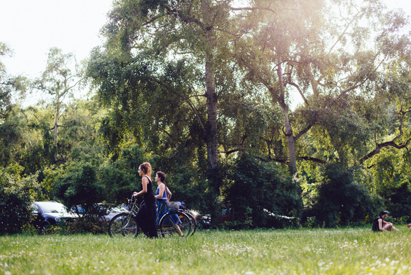 Girls passing through the park with their bicycles.