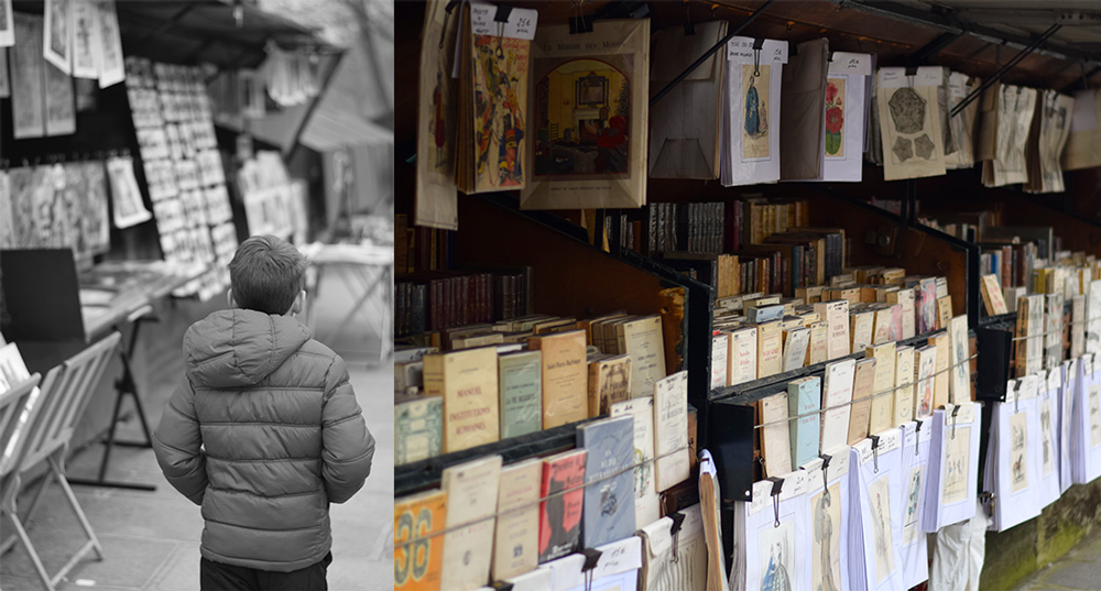 Photo of boy walking along the Seine looking at books.