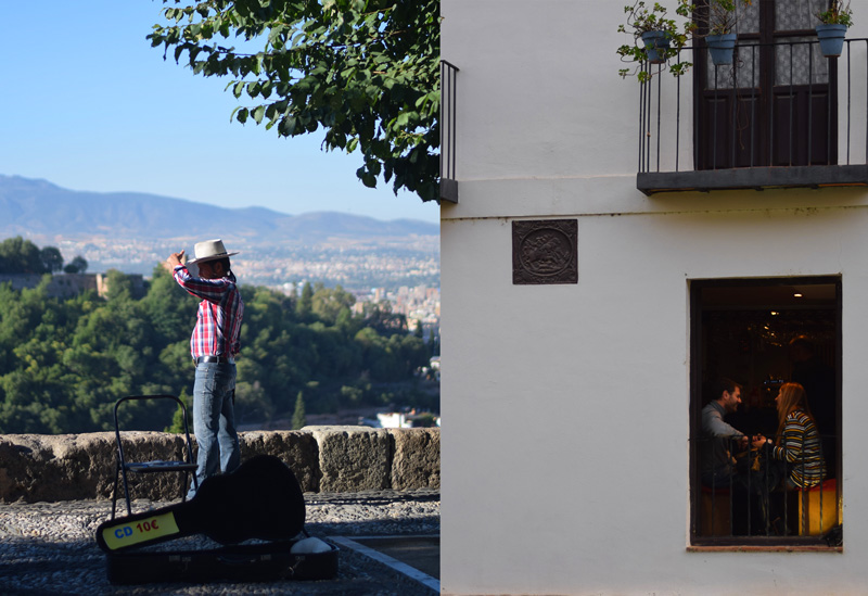 Image of Granada Spain travel including a musician in the Mirador de San Nicolas and a couple having drinks in the lower Albaicin