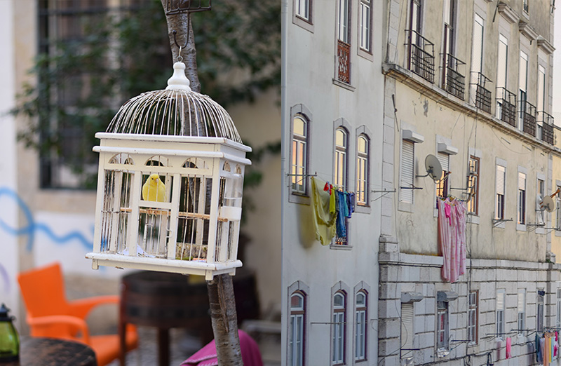 A birdcage in a plaza in Lisbon next to laundry hanging on a beautiful old building.