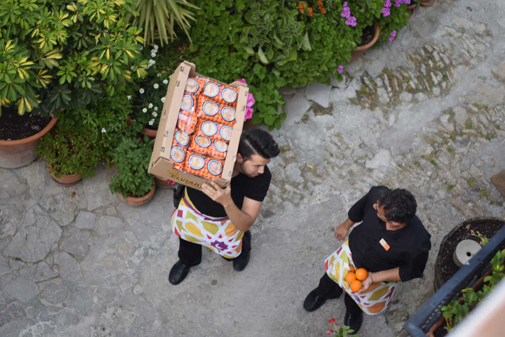 Image of Vejer de la Frontera Spain village life showing one man delivering bread and the other handling oranges