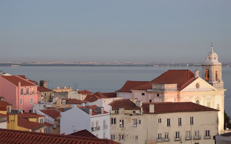 Sunset in Lisbon, Portugal. The sun is casting a warm glow over the city's buildings.