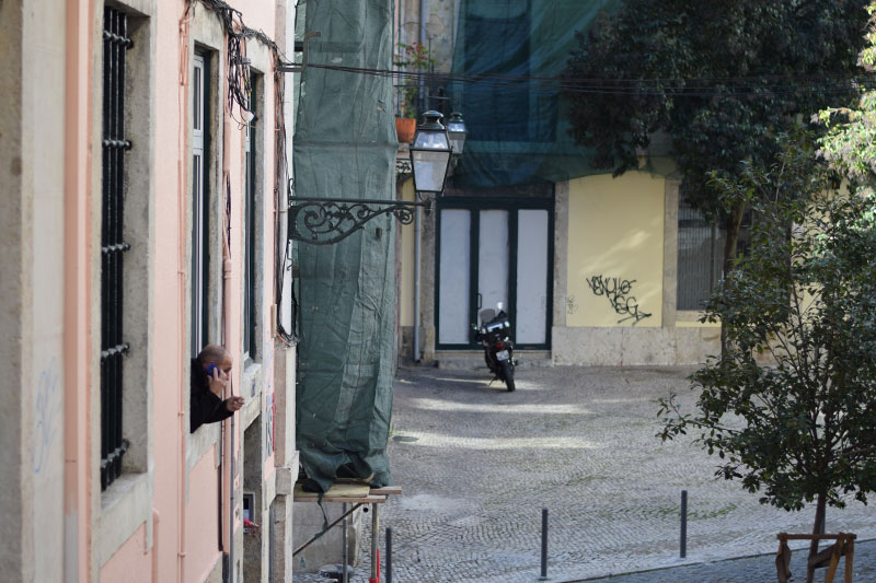 Man in Lisbon leaning out his window talking on the phone