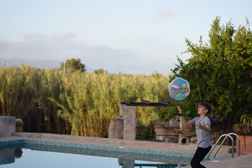 Photo of a boy playing with a ball near a pool in Mallorca Spain