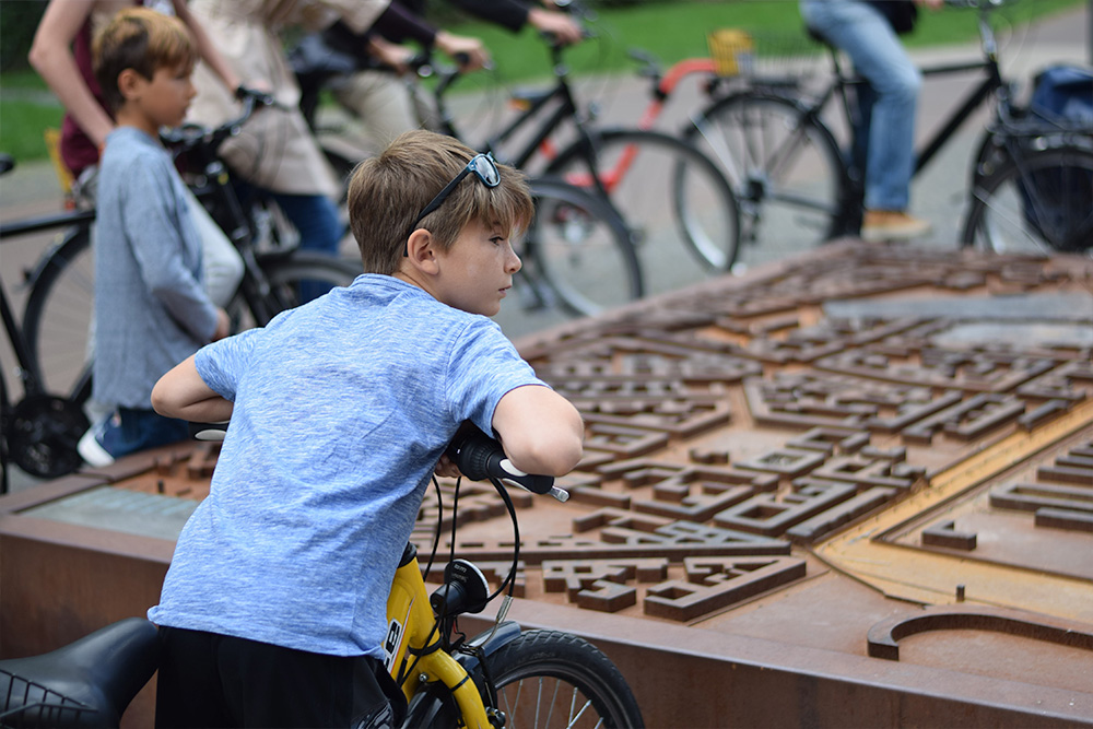 Photo of a boy looking at a map of old Berlin and the Berlin Wall while on a bicycle tour with Berlin on Bike.