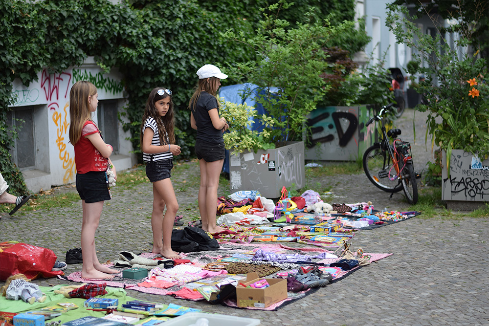 A photo of three girls in Berlin selling used clothing and other items on the streets of Penzlauer Berg in Berlin, Germany.