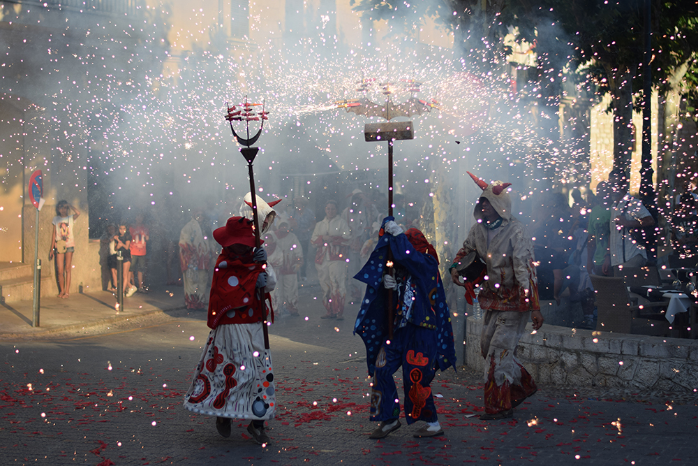 A traditional festival in the streets of Alaro, Mallorca with glimmering firecrackers and children dressed up like devils.