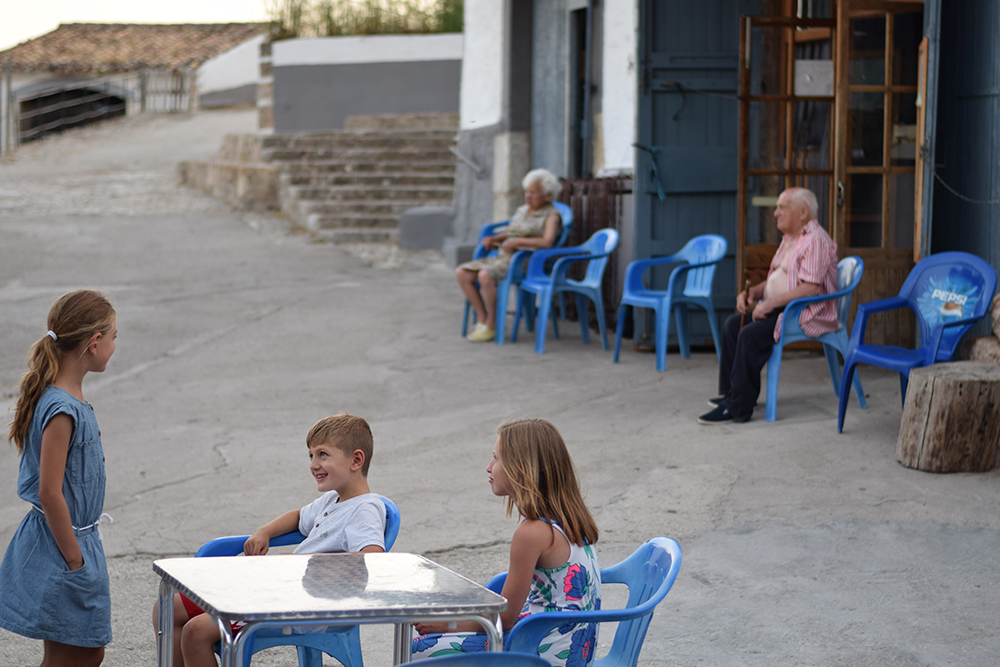 Children and elderly people sitting outside a restaurant together in Alaro, Mallorca, Spain