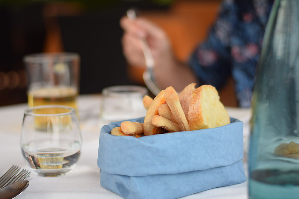 Photo of a dinner table with a blue basket of bread, water and beer in Ravello, Italy.