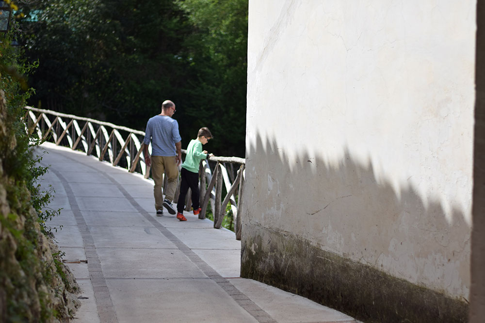 Photo of a a man walking with his son at Villa Cimbrone in Ravello, Italy.