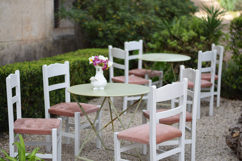 White chars with pink velvet seats nested around small tables in the garden at Finca Son Mico in Mallorca, Spain.