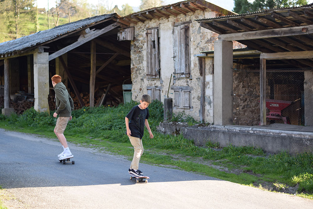 Photo of two boys on skateboards near a farmhouse in rural France.