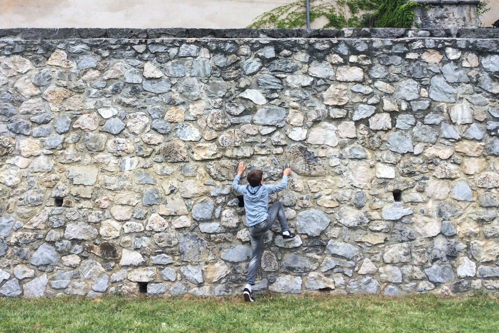 Photo of a boy climbing a stone wall.