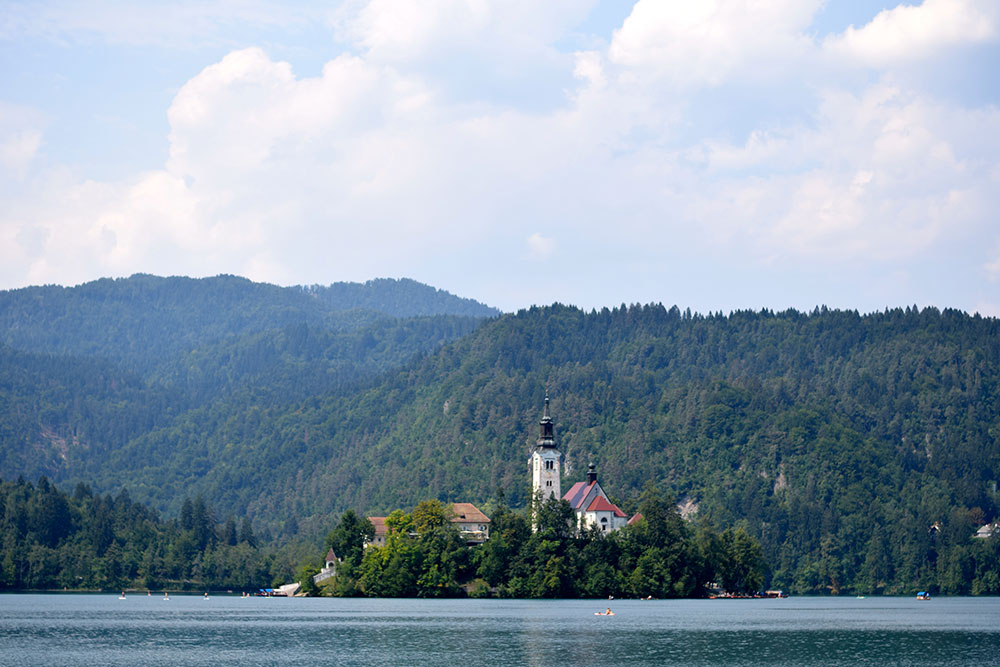 Photo of the island of Lake Bed Slovenia with its bell tower and red roofed castle.