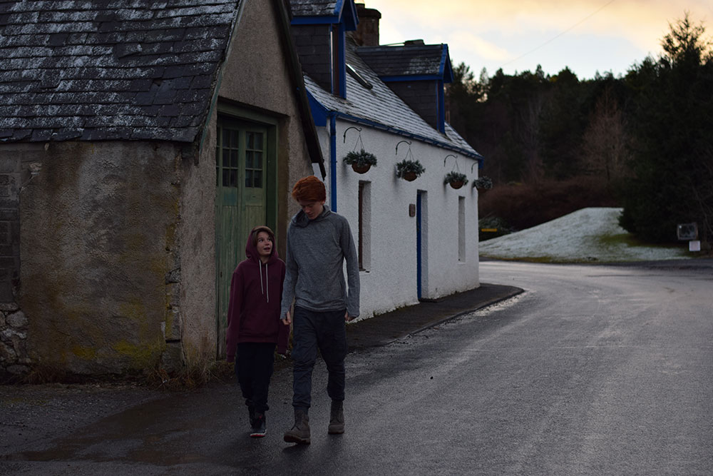 Photo of brothers walking together in the village of Cartridge, in Scotland, on a cold winter evening.