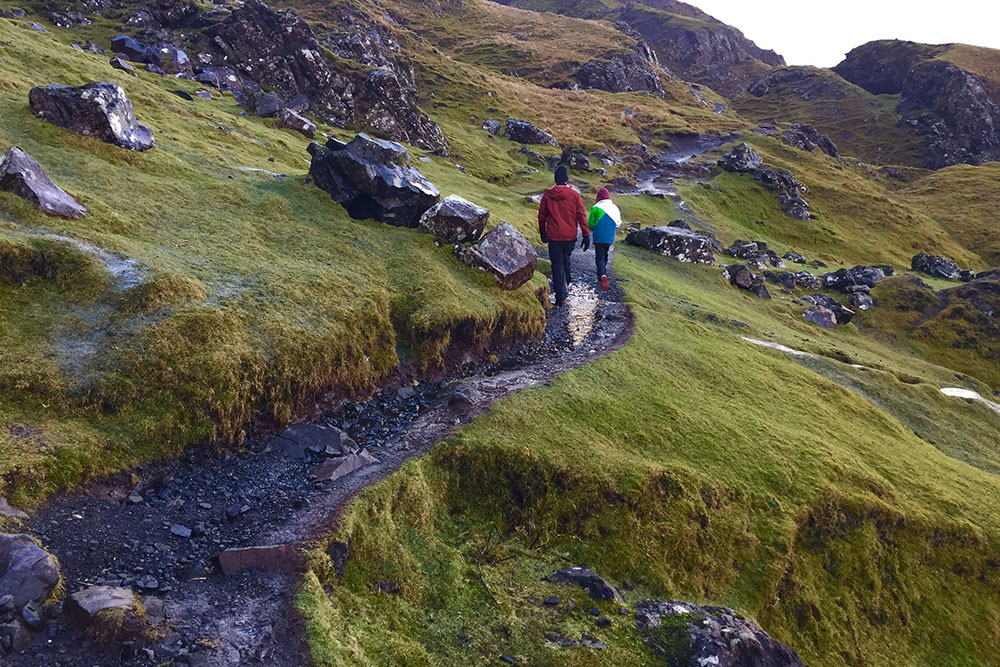 A boy and his father walking along a trail in The Quaraing on the Isle of Skye, in Scotland, in winter.