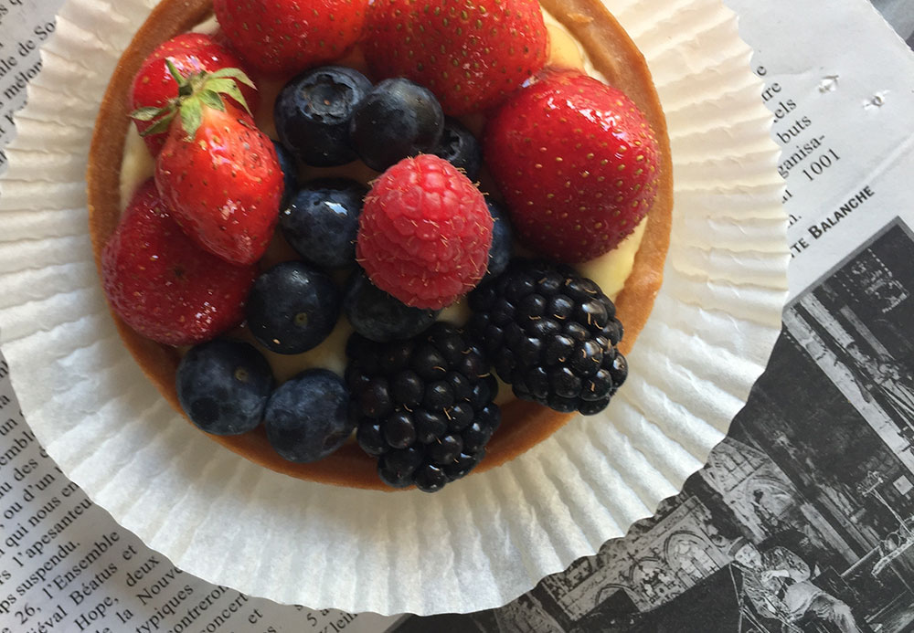 Photo of a custard tart with strawberries, blackberries, blueberries and raspberries on top.