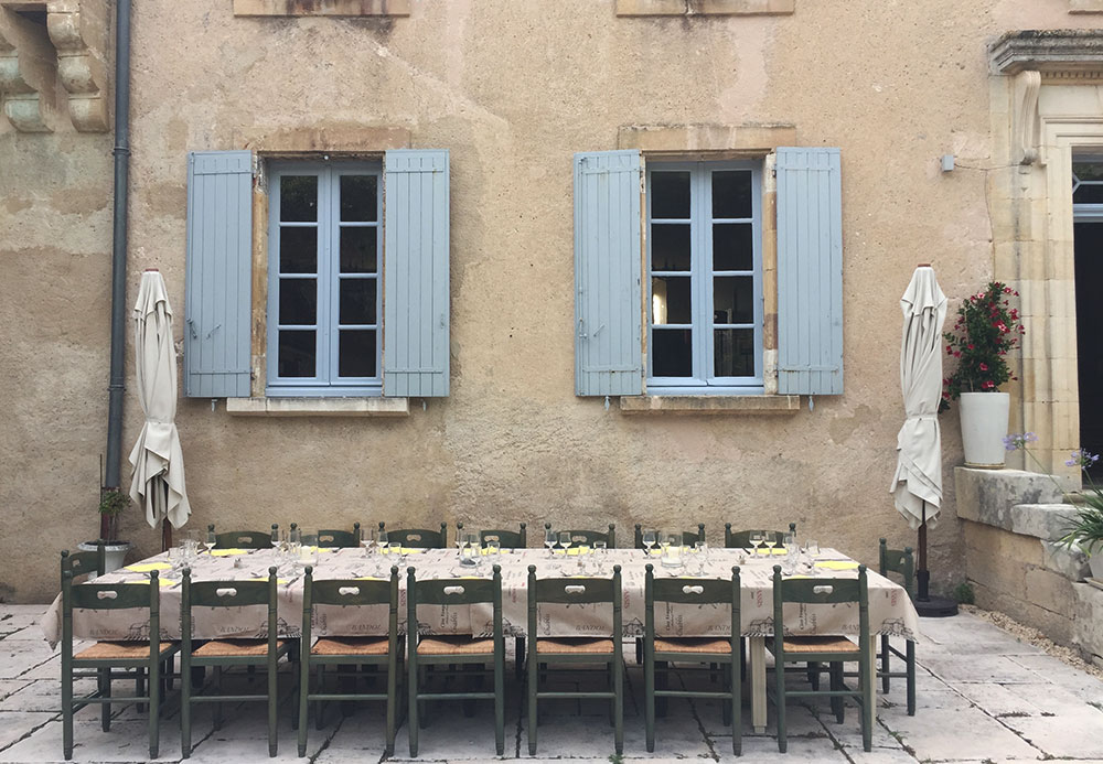 Photo of an outdoor dining table in the courtyard of a french country house.